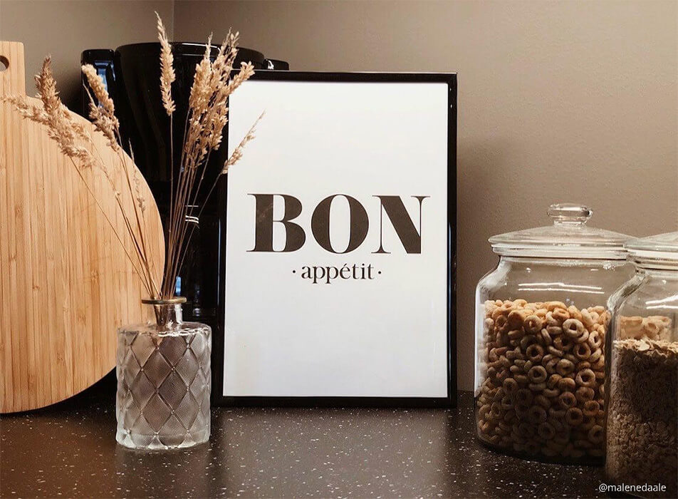 Küchenbild mit dem Text Bon appétit, Kaffeemaschine und Einmachgläser auf dunkler Arbeitsplatte